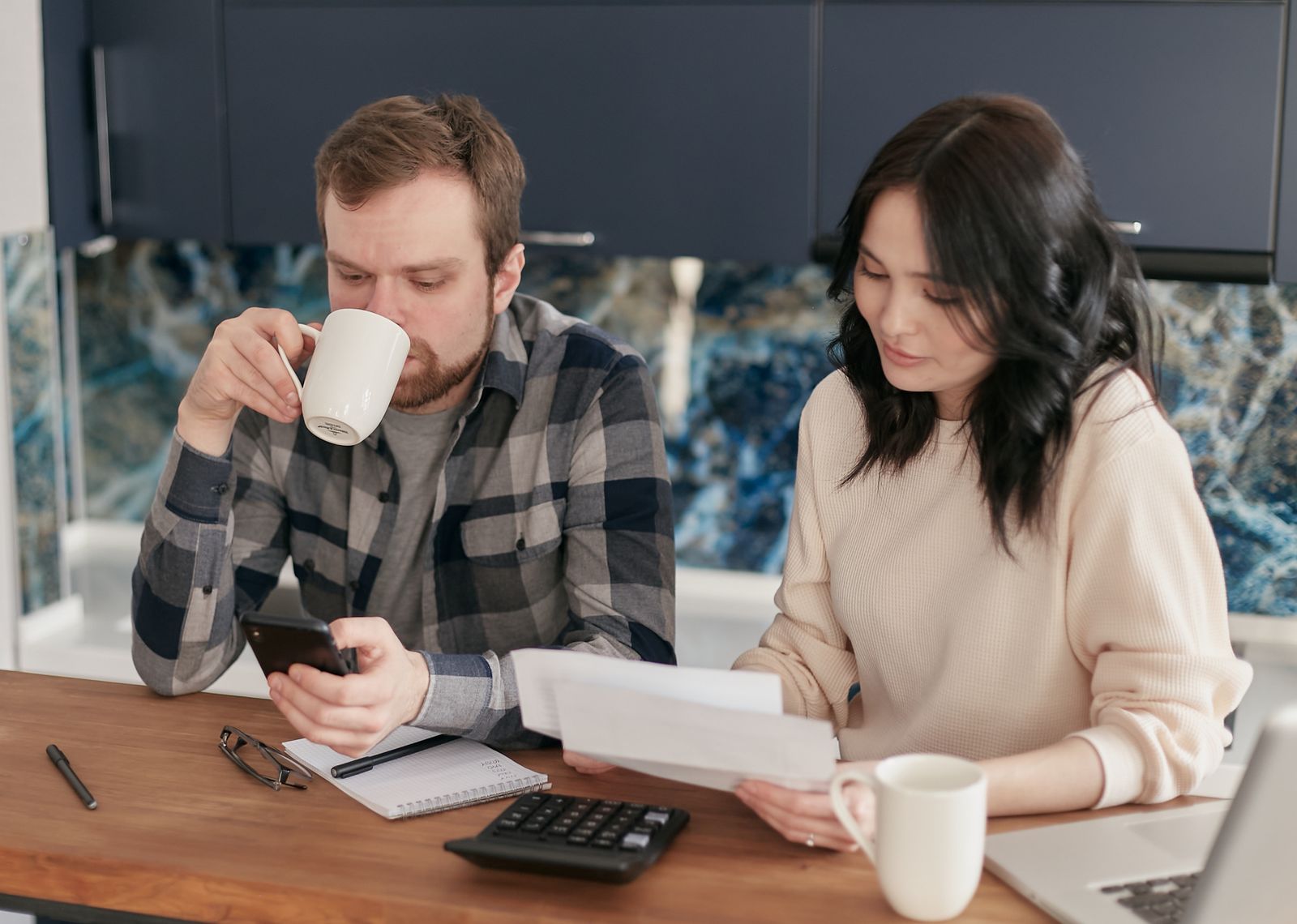 Vợ chồng đối chiếu hóa đơn, dùng máy tính và điện thoại tính tiền điện