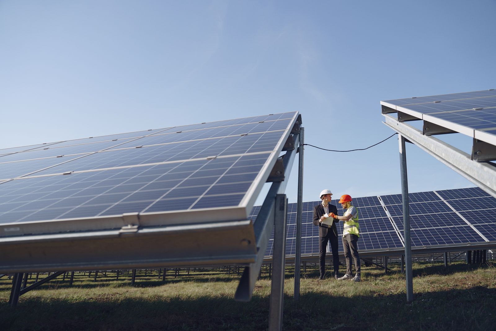 Hai kỹ thuật viên khảo sát hướng nắng giữa các dãy pin
