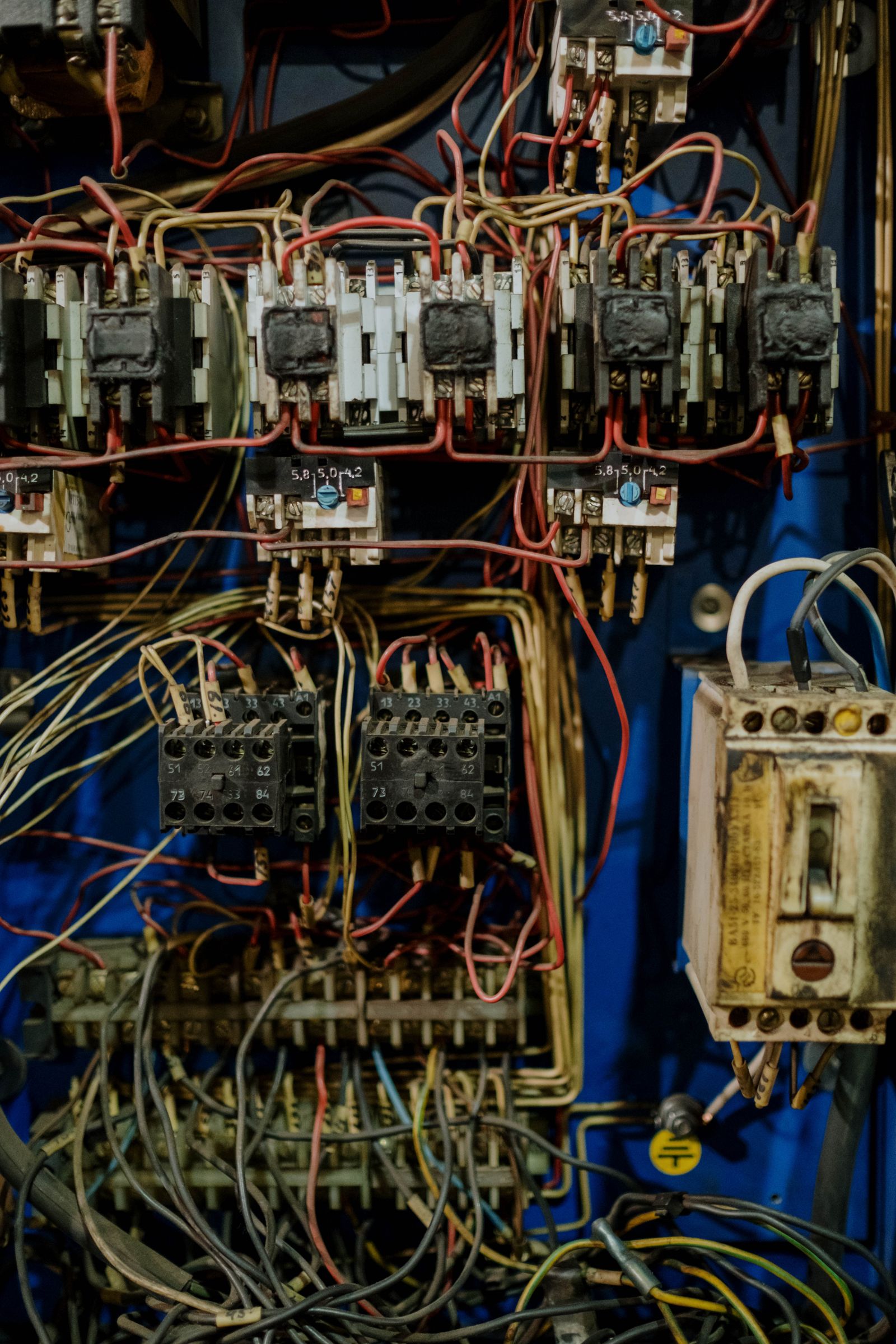 Cận cảnh bên trong tủ điện điều khiển với hàng contactor, cầu đấu dây và dây dẫn nhiều màu